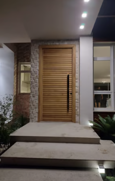 Porta veneziana em madeira clara — fachada noturna